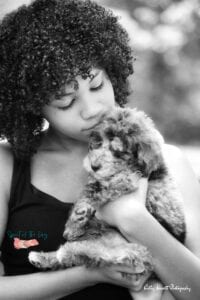curly haired woman cuddling an aussiedoodle puppy