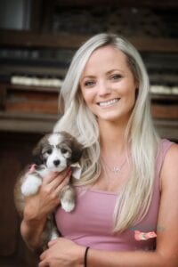 blonde lady with a pink top holding a puppy