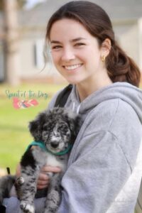 girl in a grey hoodie holding a puppy
